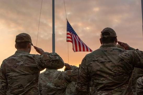 Service members salute the flag at sunset